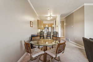 Dining area with crown molding and light colored carpet