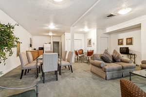 Carpeted dining space featuring a textured ceiling and baseboards