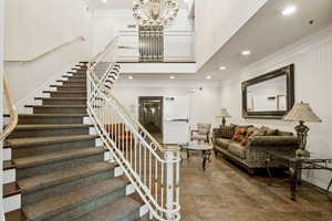 Stairs featuring ornamental molding, a high ceiling, a chandelier, and recessed lighting