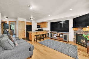 Living area featuring a fireplace, a textured ceiling, light wood-type flooring, and recessed lighting