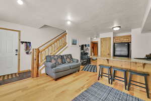 Living area featuring light wood-type flooring, stairway, and a textured ceiling