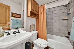 Full bathroom with toilet and shower / bath combination with curtain