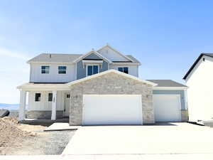 View of front facade featuring board and batten siding, a garage, driveway, and covered porch