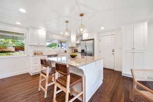Kitchen with stainless steel refrigerator with ice dispenser, dark wood-style floors, white cabinetry, and recessed lighting