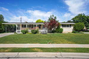 Single story home featuring covered porch, brick siding, driveway, a front yard, and an attached carport