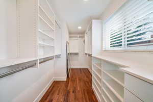 Walk in closet with dark wood-style floors
