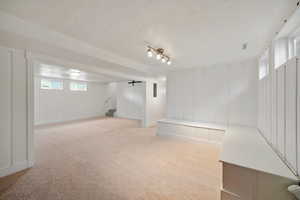 Below grade area with light colored carpet, a textured ceiling, and stairs