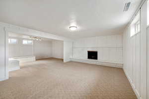 Basement with carpet, a textured ceiling, and a brick fireplace