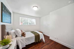 Bedroom with dark wood-style flooring and baseboards