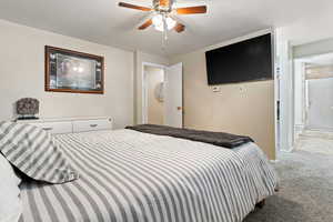 Bedroom featuring light colored carpet, ensuite bath, and a ceiling fan