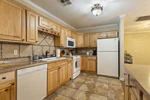 Kitchen featuring white appliances, decorative backsplash, ornamental molding, and light stone finish floors