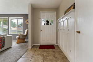 Carpeted entrance foyer with tile patterned flooring and baseboards