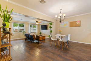 Dining space with wood finished floors, crown molding, a chandelier, and ceiling fan