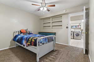 Bedroom with washer and clothes dryer, carpet, and a ceiling fan