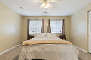 Bedroom with carpet flooring, multiple windows, and a ceiling fan