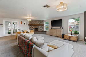 Living room featuring plenty of natural light, french doors, carpet, and a fireplace