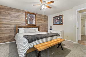 Bedroom featuring wood walls, light carpet, and ceiling fan