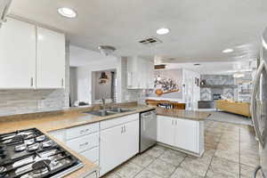 Kitchen with appliances with stainless steel finishes, light countertops, a peninsula, open floor plan, and white cabinets