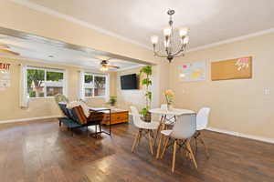 Dining room featuring ceiling fan, dark wood-style floors, ornamental molding, and a chandelier
