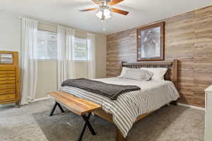 Bedroom with wooden walls, carpet, and ceiling fan