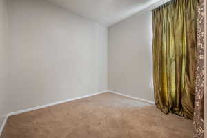 Empty room with lofted ceiling and light colored carpet