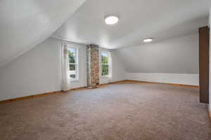 Additional living space with vaulted ceiling and carpet