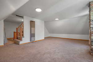 Bonus room with a heating unit, carpet floors, lofted ceiling, and stairway