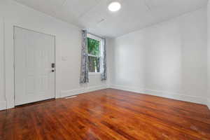 Foyer entrance with crown molding and wood-type flooring