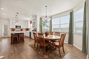 Dining space with plenty of natural light, a chandelier, light wood-style floors, a textured ceiling, and recessed lighting