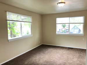 Carpeted spare room featuring baseboards