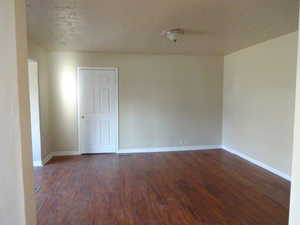 Unfurnished room with dark wood finished floors and a textured ceiling