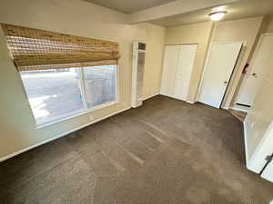 Unfurnished bedroom with a heating unit and dark colored carpet