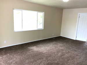 Empty room with dark carpet and healthy amount of natural light