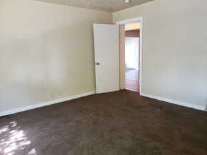 Spare room with dark colored carpet and a textured ceiling