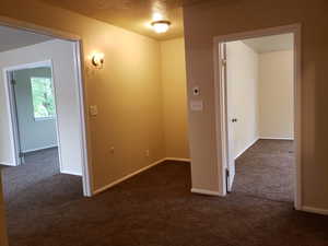 Hall featuring dark carpet and baseboards