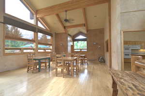 Dining space featuring high vaulted ceiling, light wood-style floors, healthy amount of natural light, ceiling fan, and beam ceiling