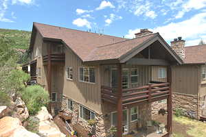 Condo featuring a shingled roof, stone siding, a chimney, and board and batten siding