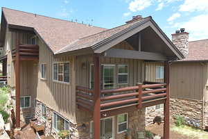 Condo with a shingled roof, stone siding, board and batten siding, and a balcony