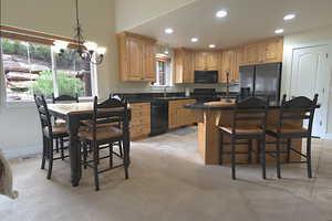 Kitchen featuring black appliances, a chandelier, light brown cabinetry, recessed lighting, and dark countertops