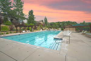 Community pool at dusk with a pergola, and a patio