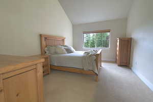 Bedroom featuring lofted ceiling and light carpet