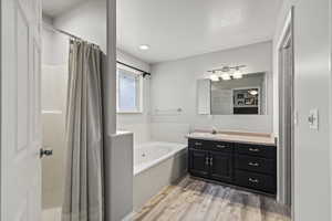Bathroom with a garden tub, vanity, wood finished floors, and a shower with shower curtain