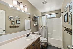 Full bath with vanity, shower / bathtub combination with curtain, tile patterned flooring, and a textured ceiling
