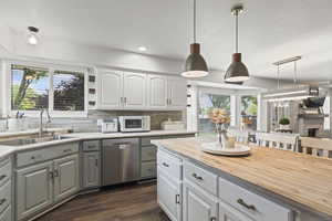 Kitchen with dishwasher, butcher block counters, white microwave, plenty of natural light, and recessed lighting