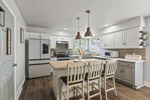 Kitchen featuring white appliances, wood counters, decorative backsplash, under cabinet range hood, and dark wood finished floors
