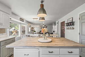 Kitchen with butcher block counters, white cabinetry, ceiling fan, and a kitchen island