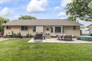 Rear view of property with entry steps, a patio, and a lawn