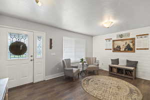 Entrance foyer with dark wood-style flooring and a textured ceiling