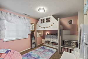 Bedroom featuring carpet, a textured ceiling, and freestanding refrigerator