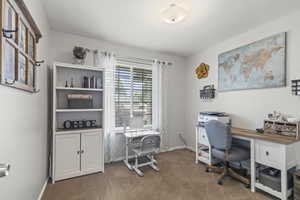 Carpeted home office featuring baseboards